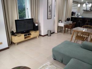 Santubong Suites Sejinjang في كوتشينغ: غرفة معيشة مع تلفزيون بشاشة مسطحة وأريكة