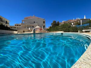 a swimming pool with blue water in front of a building at Olhos do mar 209 grande terraço vista mar in Olhos de Água