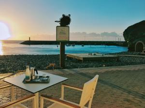 uma mesa e uma cadeira na praia com o pôr do sol em De Sebastian 1 - estudio frente al mar em San Nicolás