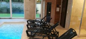 three black chairs sitting next to a swimming pool at Balaton&Center Wellness Apartman in Siófok
