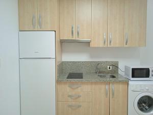 a kitchen with a white refrigerator and a sink at Seville Luxury Apartment Parking Opcional in Bormujos