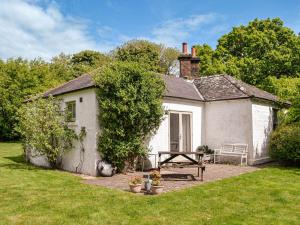 una pequeña casa blanca con una mesa de picnic en un patio en Milnfield Cottage en Annan