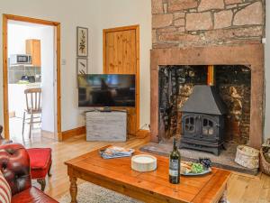 a living room with a fireplace and a table with a bottle of wine at Milnfield Cottage in Annan