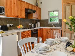 una cocina con una mesa con copas de vino. en Milnfield Cottage en Annan