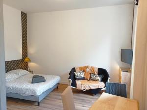 a bedroom with a bed and a chair and a tv at Le 28 Frater in Millau