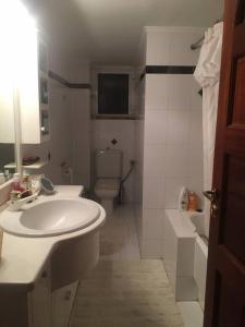 a white bathroom with a sink and a toilet at Sea view luxury apartment in Aiándion