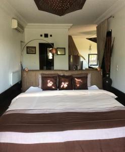 1 dormitorio con 1 cama grande con almohadas marrones en Villa Mano, en Marrakech