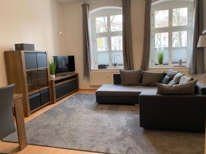a living room with a couch and a tv at Viadrina Rooms & Apartments Frankfurt-Oder am Park im Zentrum in Frankfurt Oder