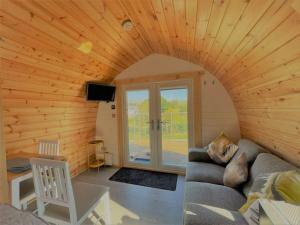 sala de estar con sofá en una habitación con paredes de madera en Burnbank Glamping Pod, en Acharacle