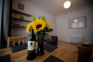 a bottle of wine and a vase of flowers on a table at Armadale Apartment in Fort William