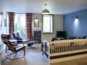 a room with a crib and a living room at Red Gable Cottage in Shap