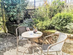 a table with two chairs and two glasses of wine at Red Gable Cottage in Shap