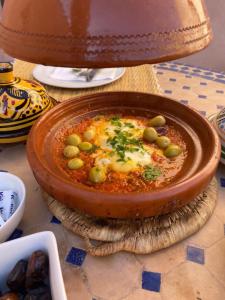 eine Schüssel Suppe mit Oliven und Käse auf dem Tisch in der Unterkunft Auberge Kasbah Des Dunes in Merzouga