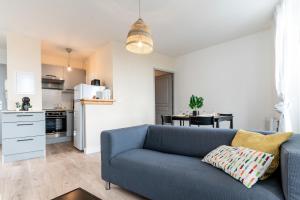 a living room with a blue couch and a kitchen at Appartement Terreau in Manosque