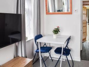 a small white table and two blue chairs in a room at Sea Breeze in Cliftonville