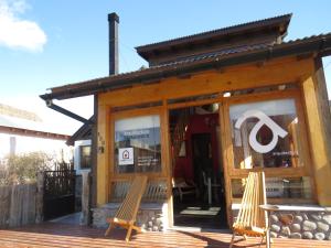 a wooden building with two chairs on a deck at CasaEstudio in El Chalten