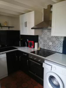 a kitchen with a washing machine and a washer at Chez kathie in Arrest