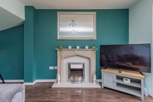 a living room with a fireplace and a flat screen tv at Central Townhouse Tipton - Sleeps 8 - Ideal for Contractors & Families in Tipton