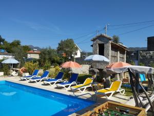 un grupo de sillas y sombrillas junto a una piscina en Alojamento de Crasto - Gerês en Geres
