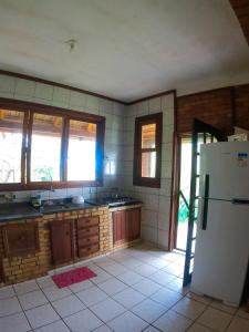 a kitchen with a refrigerator and some windows at Casa Praia da Gamboa in Garopaba