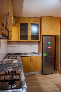 a kitchen with wooden cabinets and a stainless steel refrigerator at Helton´s Residence in Praia