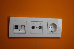 um interruptor de luz branco numa parede laranja em Helton´s Residence em Praia