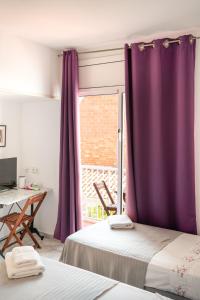 a room with two beds and a window with purple curtains at Hostal Bonanza in Sitges