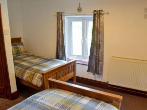 1 dormitorio con 2 camas y ventana en Tree Tops Cottage, en Mundford