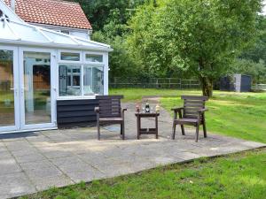 un patio con 2 sillas y una mesa junto a una casa en Tree Tops Cottage, en Mundford