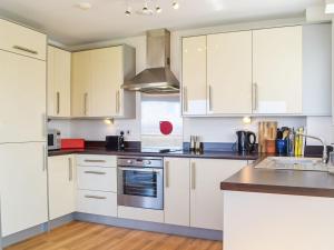 a kitchen with white cabinets and a stove top oven at Bayview in Llanelli