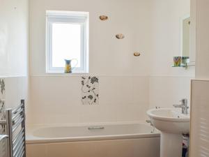 a white bathroom with a tub and a sink at Bayview in Llanelli