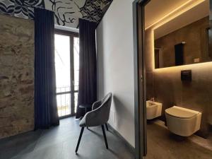 bagno con specchio, sedia e lavandino di Sant'Andrea - Luxury Rooms in Vucciria a Palermo