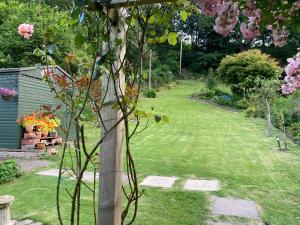 um jardim com um poste de madeira na relva em Maple Bank Country Guest House em Keswick