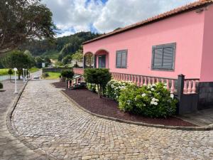 un edificio rosa con arbustos junto a un camino de ladrillo en Quinta do Avô Dimas - Rural Home - São Brás, en Porto Formoso