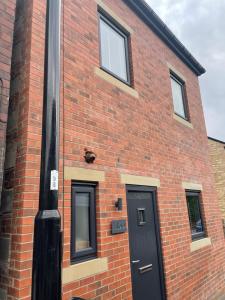 a black door on the side of a brick building at Nirvana house, 3 bedroom, 3 level riverside location in Deepcar