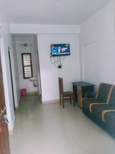 a living room with a couch and a tv on the wall at KK Residency in Perintalmanna