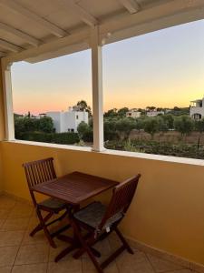 a table and a chair on a balcony with a window at Emmanouil in Kythira