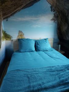 a bed with blue pillows in a cave at Le Canari in Huisnes-sur-Mer