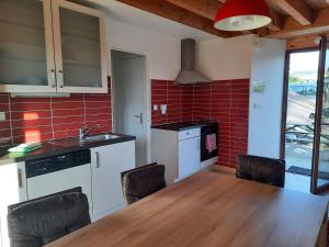 een keuken met een tafel en stoelen en rode tegels bij Le Canari in Huisnes-sur-Mer