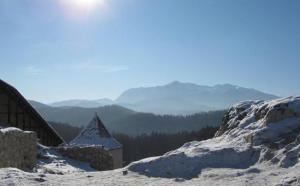 a snow covered hill with a building and mountains in the background at Pensiunea Rosenau in Râşnov