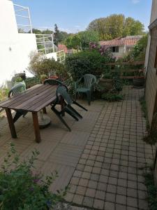 una mesa de picnic de madera y sillas en un patio en Le 8, en Pouzauges