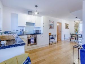 a kitchen and living room with white cabinets and a table at Vineyards Apartment in Ely