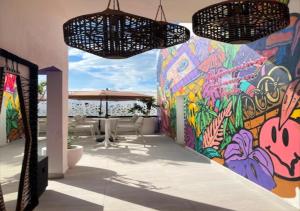 a wall with a painting on it with tables and umbrellas at Auténtico Vertical Playa del Carmen in Playa del Carmen