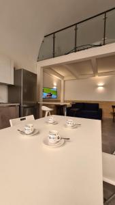 a white table with cups and saucers on it at La Giara House in Corato