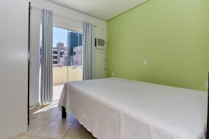 ein Schlafzimmer mit einem großen Bett und einem großen Fenster in der Unterkunft 791 - Cobertura com piscina. 200m da PRAIA. BOMBINHAS - CENTRO in Bombinhas
