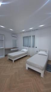 two beds in a large room with wooden floors at Villa de luxe sans vis-à-vis à 2 min de la plage in Djerba