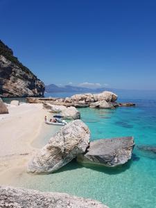 a beach with large rocks and a beach with people on it at Appartamento Limone in Cala Gonone