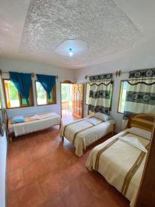 - 2 lits dans une chambre dotée de rideaux bleus dans l'établissement El Mirador de Tansu, à Lanquín
