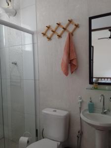y baño con aseo, lavabo y espejo. en Terral Casa de Praia, en Guarujá
