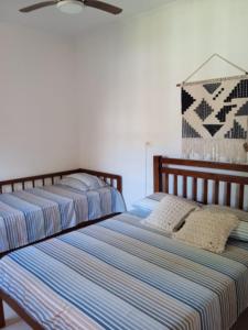 - 2 lits installés l'un à côté de l'autre dans une chambre dans l'établissement Terral Casa de Praia, à Guarujá